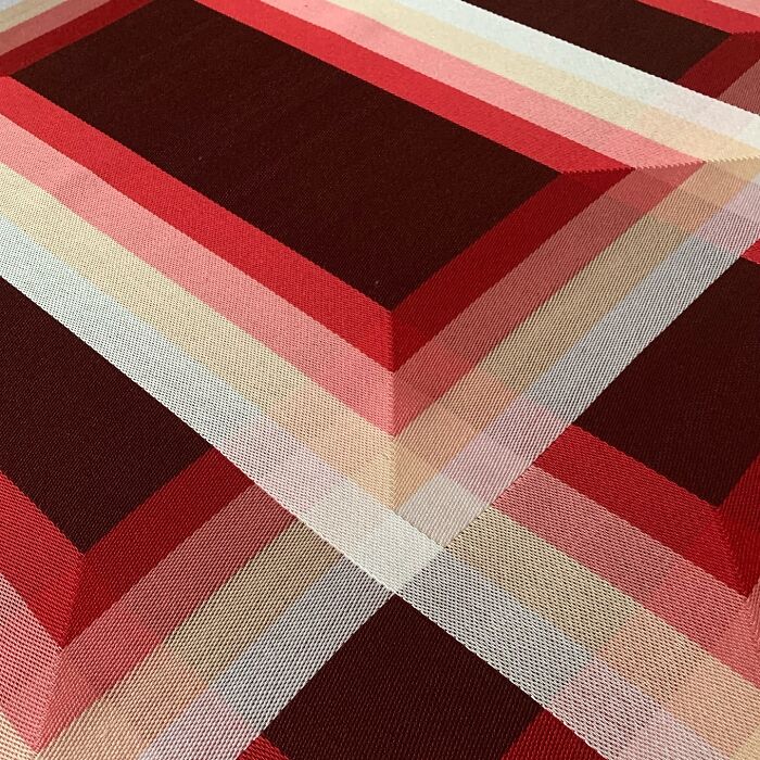 Intricate geometric weave art in red and pink shades, creating a stunning optical illusion.