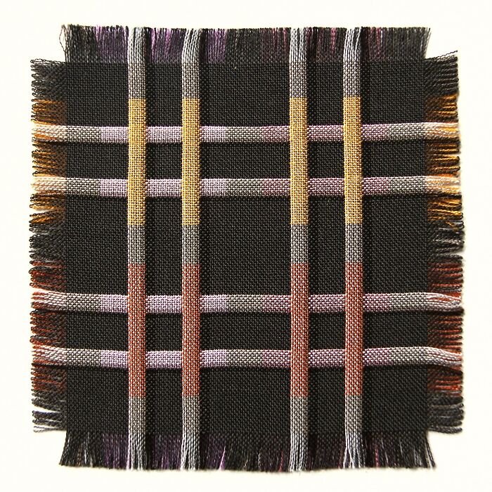 Intricate geometric weave art with colorful intersecting lines on a black fabric background.