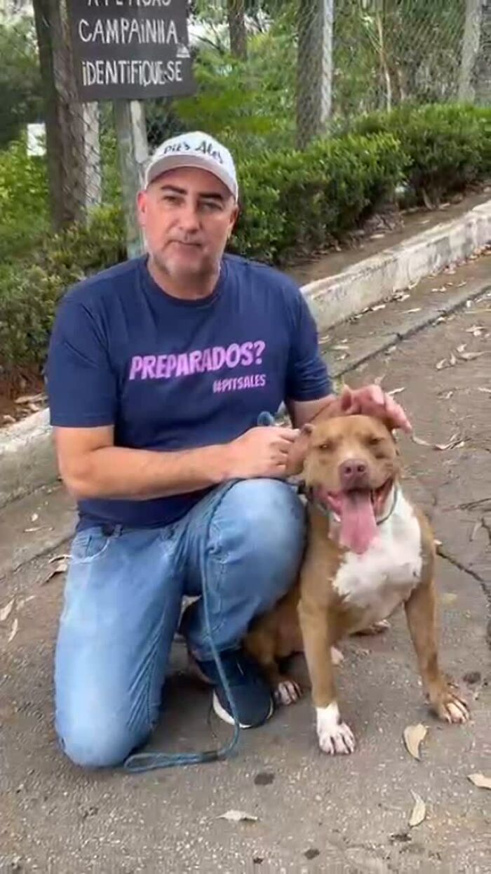 Man kneeling with a smiling Pit Bull in an outdoor setting, supporting pit bull rescue efforts. Man kneeling with a smiling Pit Bull in an outdoor setting, supporting pit bull rescue efforts.