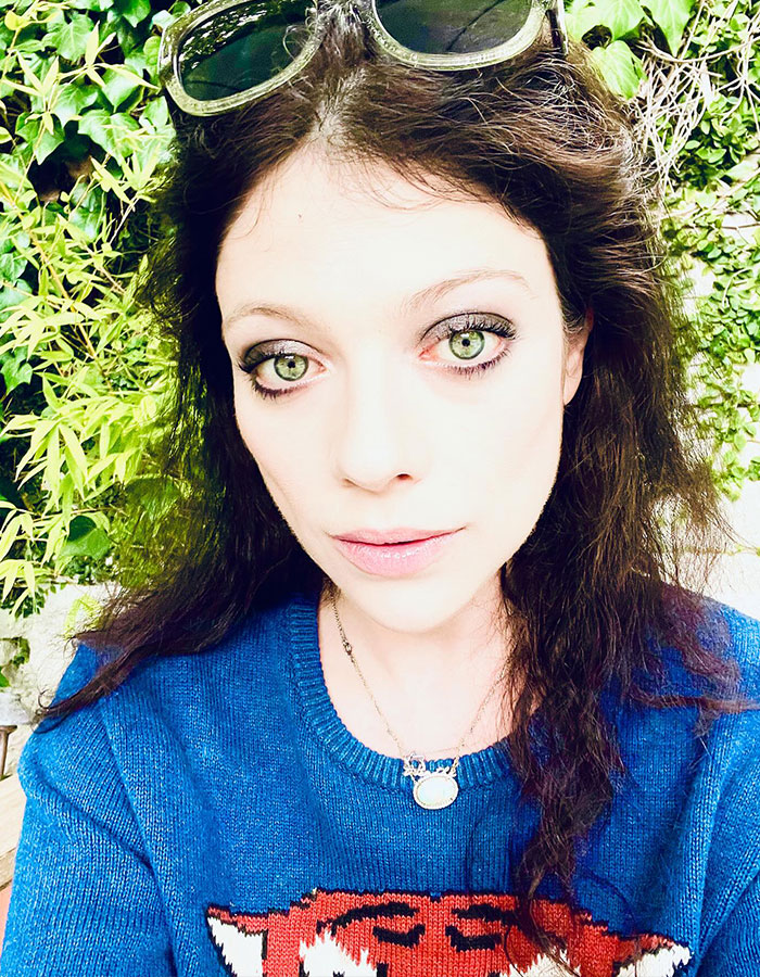 Young woman in a blue sweater with tiger design, wearing sunglasses on her head, posing outdoors. Young woman in a blue sweater with tiger design, wearing sunglasses on her head, posing outdoors.