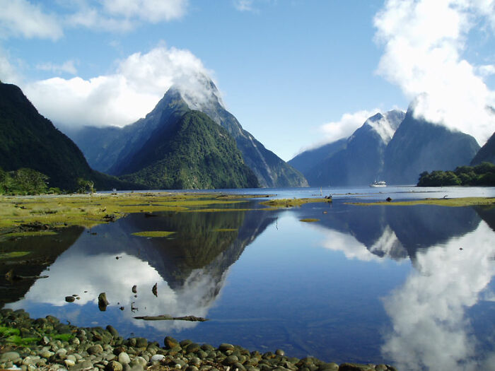 Serene natural wonders with mountains and a peaceful lake reflecting clouds in the sky.