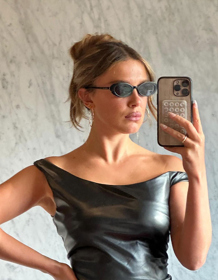 Person taking a selfie in black off-shoulder dress and small sunglasses. Person taking a selfie in black off-shoulder dress and small sunglasses.