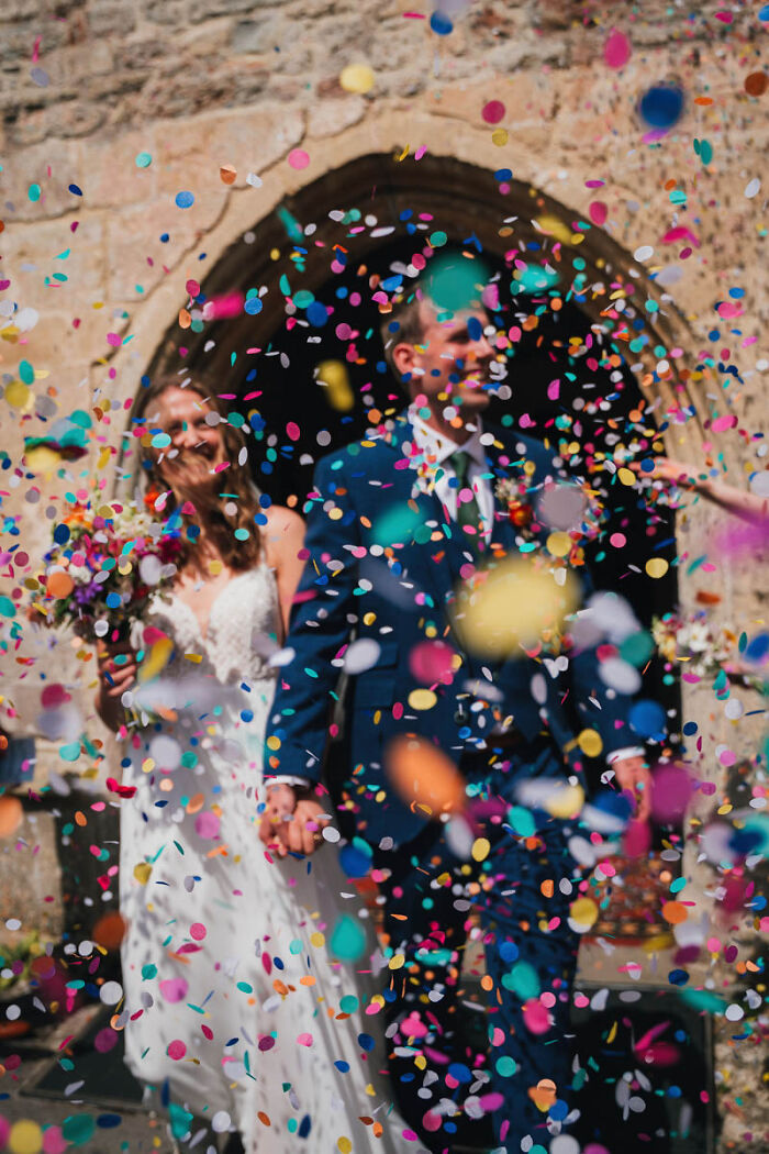 Confetti shower over a newlywed couple in a wedding photograph.