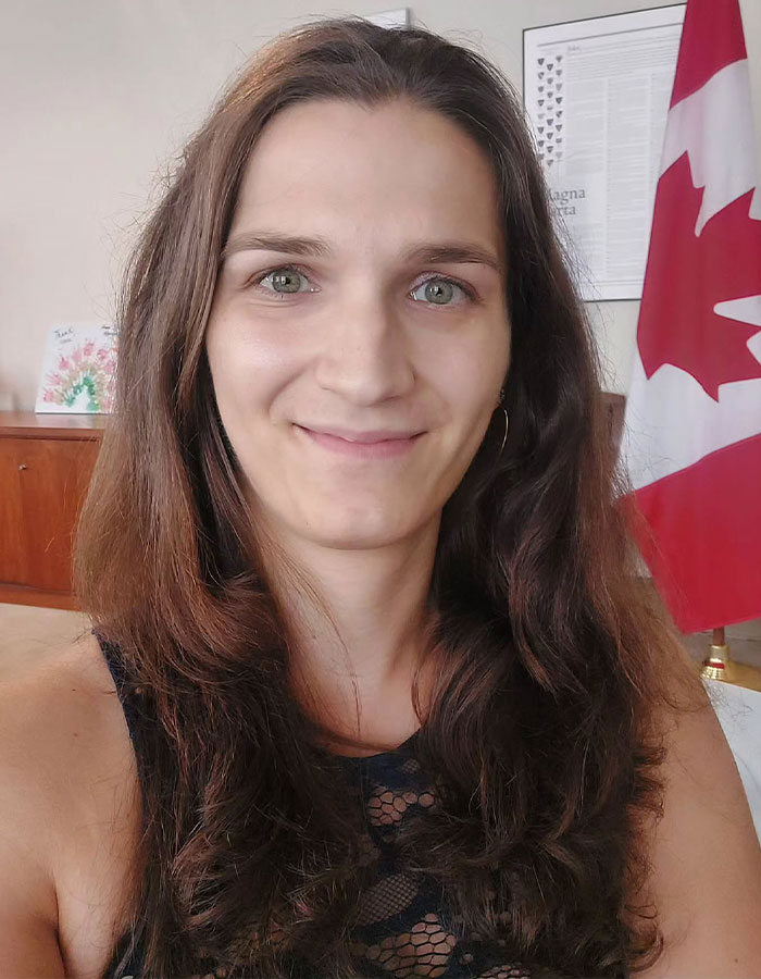 Person advocating for transgender inclusion in sports, standing in front of Canadian flag, in an indoor setting.