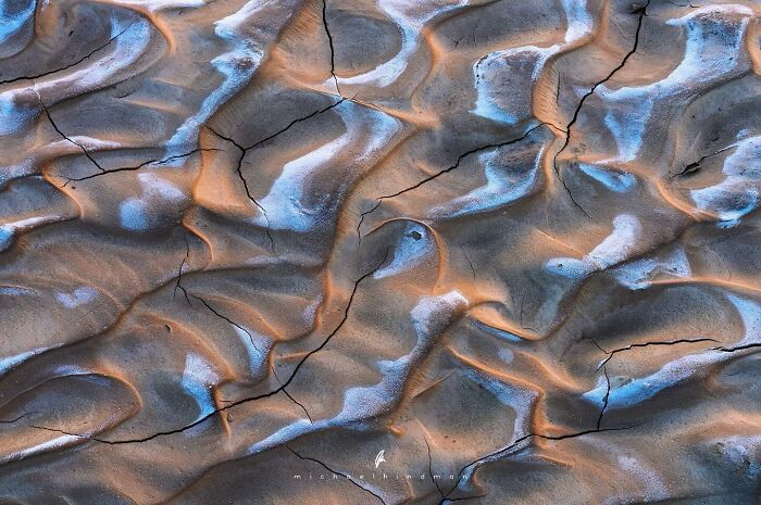 Textures of nature with c*****d, patterned ground in orange and blue hues, creating an intimate landscape photograph.