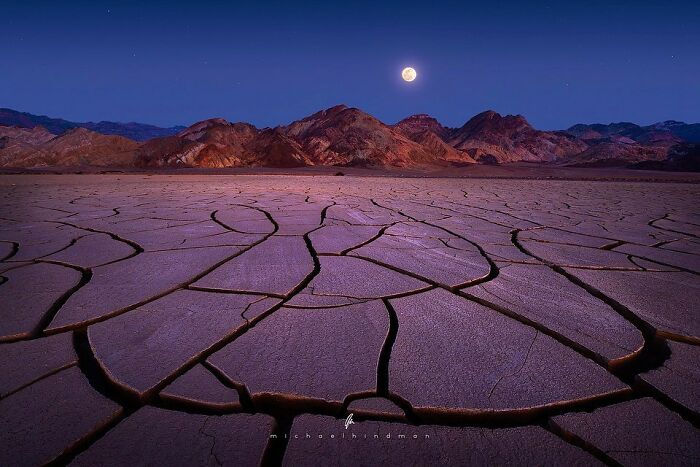 C*****d earth under moonlight, highlighting nature's textures near rugged mountains.