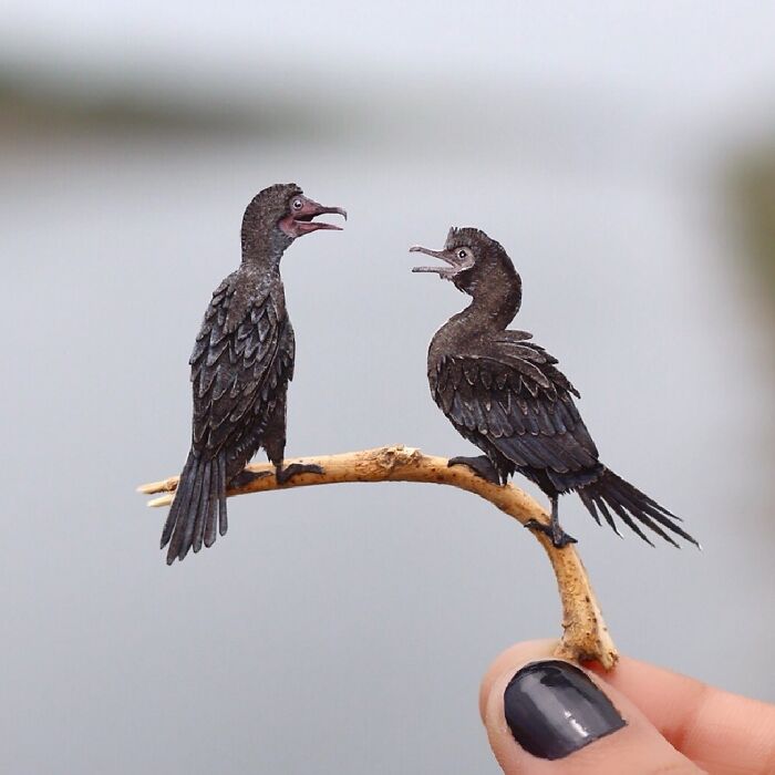 Miniature realistic paper art of two birds on a branch, highlighting animal conservation efforts.