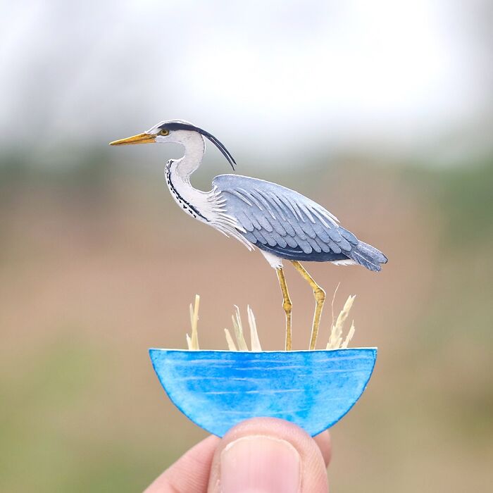 Miniature realistic paper art of a heron created by artists for animal conservation awareness.