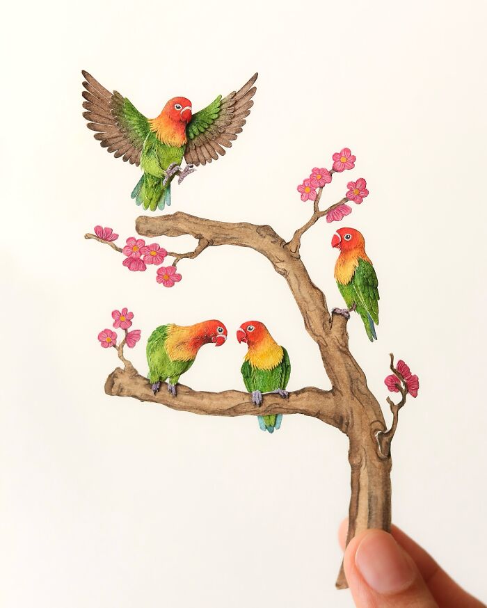 Miniature realistic paper art of colorful birds on a flowering branch, showcasing intricate details.