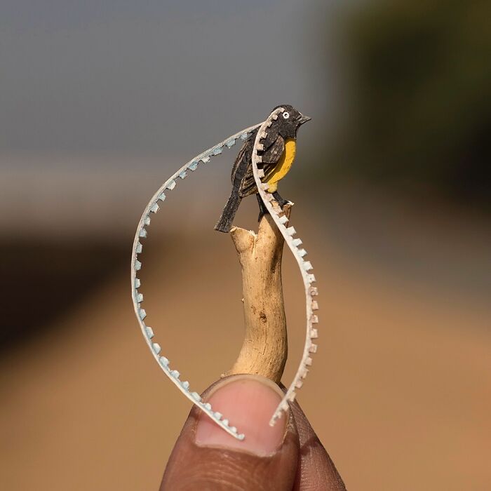 Miniature realistic paper art depicting a bird perched on a twig, created to engage in conservation dialogue.
