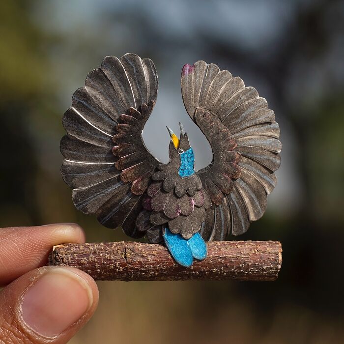 Miniature realistic paper art of a bird perched on a twig, created to spark conversation about conservation.