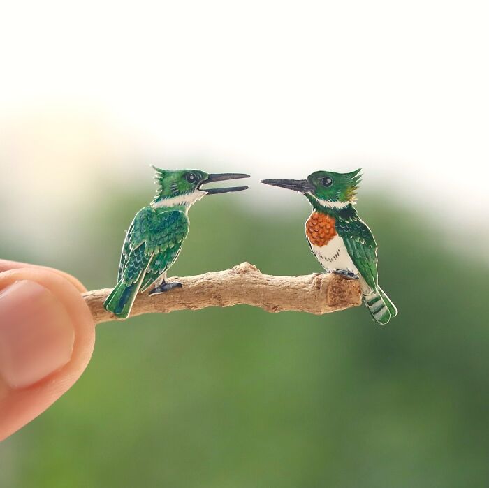 Miniature realistic paper art of birds perched on a small branch, highlighting animal conservation through artistic expression.