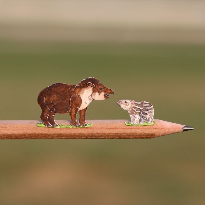 Miniature realistic paper art animals on pencil tip, highlighting conservation.