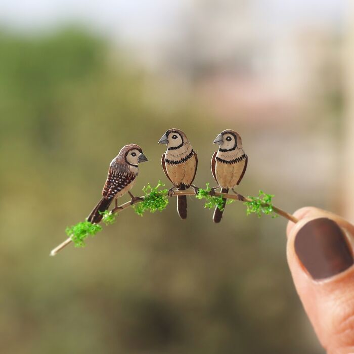 Miniature realistic paper art of three birds on a twig, created to promote conservation awareness.