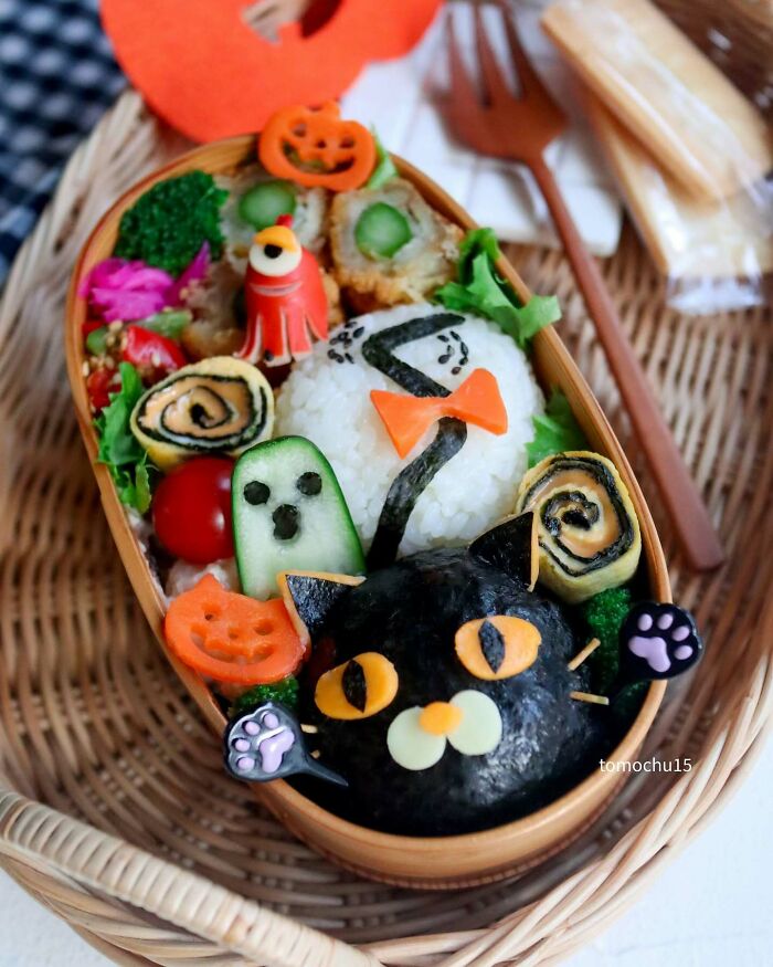 Creative lunchbox art featuring a Halloween-themed bento with a black cat and festive decorations.