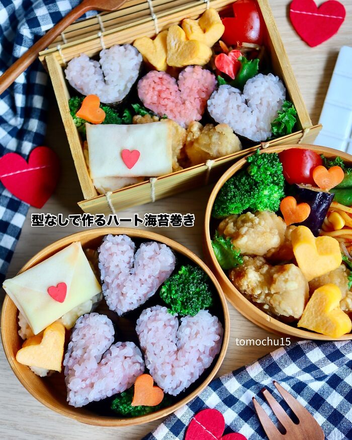 Creative Japanese lunchbox with heart-shaped rice, vegetables, and decorative elements in a bento style.