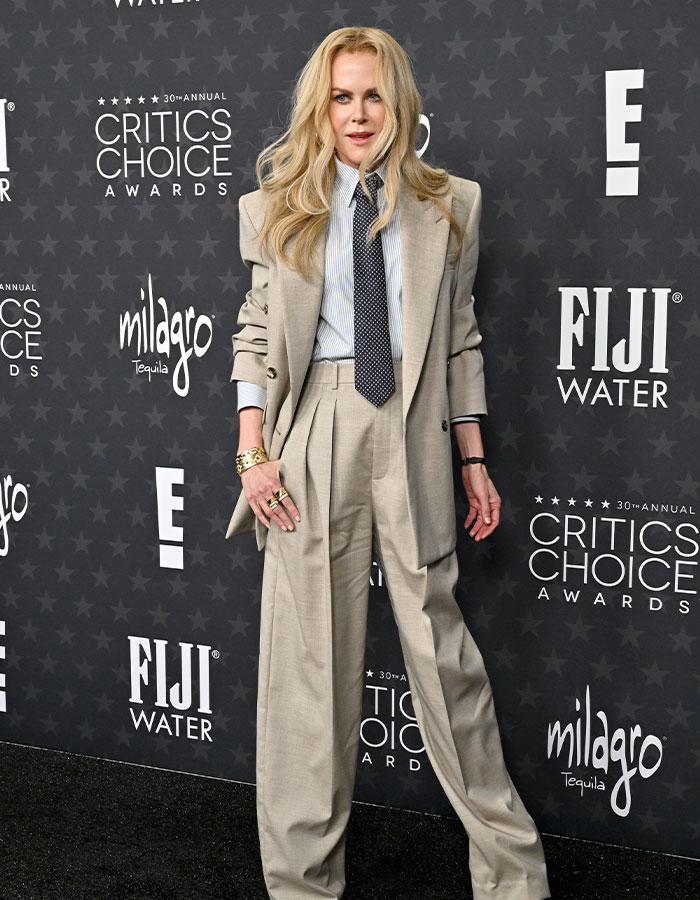 Celebrity in a tan suit at the Critics Choice Awards red carpet, showcasing daring fashion choices.