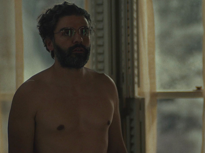 Oscar Isaac without prosthetics in a dim-lit room, showcasing a natural, unfiltered look on screen.
