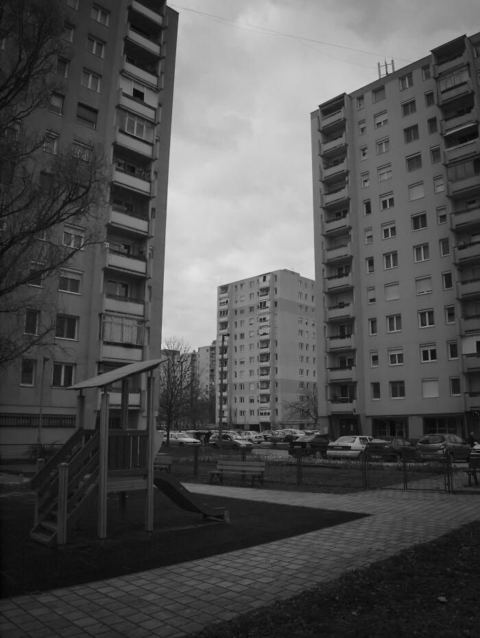 Hungary's panel buildings with a playground in the foreground, captured in black and white.