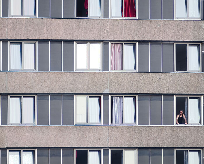 Hungarian panel building façade with open windows and a person looking out.