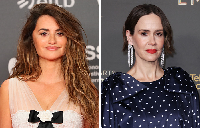 Penélope Cruz and Sarah Paulson at a red carpet event, one in a white dress, the other in a polka-dot outfit.