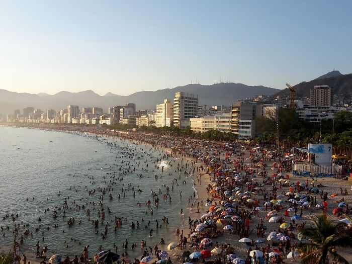 Retro Brazilian beach scene with sunbathers and colorful umbrellas lining the shoreline.