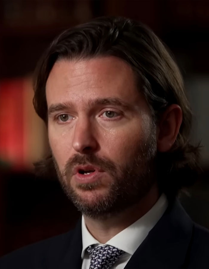 Royal aide discussing Prince William&rsquo;s reaction in a formal setting, wearing a suit and tie, with a serious expression.