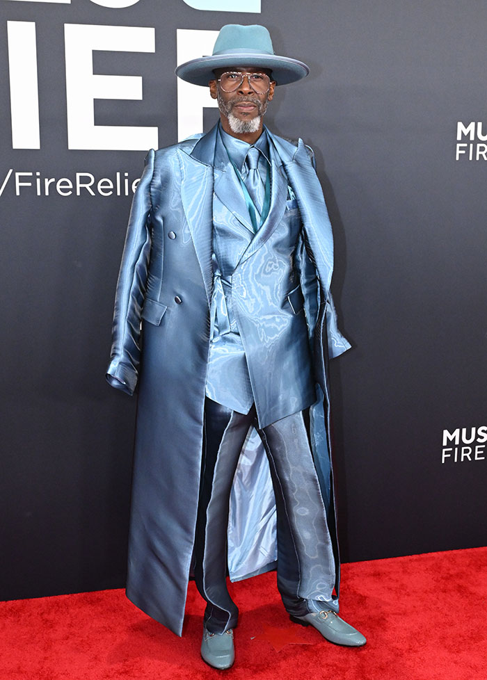Man in stylish blue suit and hat on the red carpet at the Grammy Awards, showcasing a standout fashion outfit.