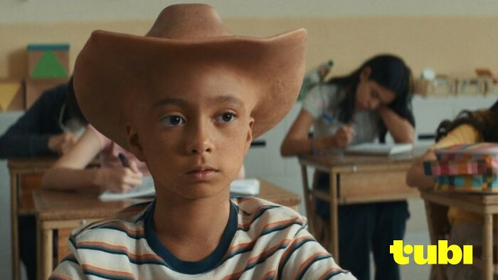 Young boy in a classroom wearing a large hat, with Tubi logo, depicting a disturbing ad moment.