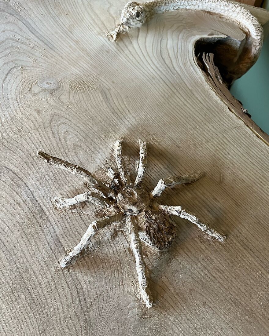 Chainsaw artist creates intricate spider sculpture carved from a log, showcasing detailed craftsmanship.