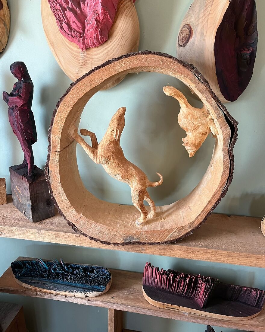 Chainsaw artist's intricate log sculpture of two animals inside a wooden circle, displayed on a shelf.