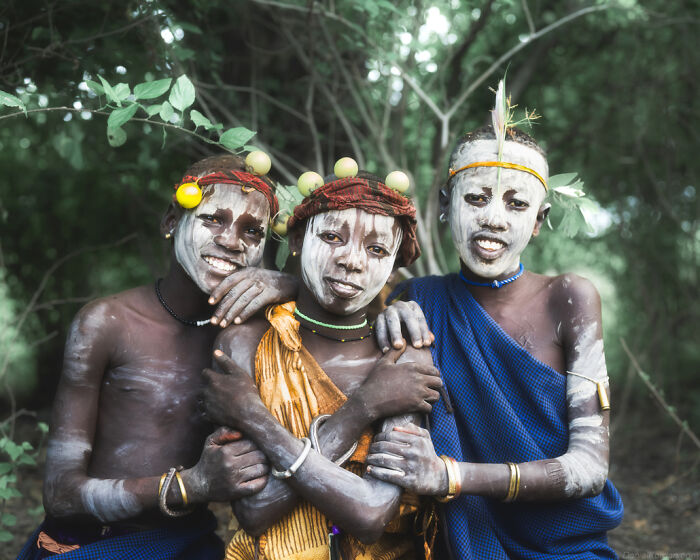 Ethiopian people with traditional body paint and adornments, standing together in a natural setting.