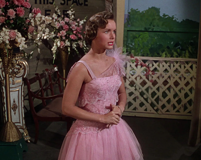 A woman in a pink dress in a historical movie scene with floral decoration, showing how Hollywood sometimes misrepresents history.