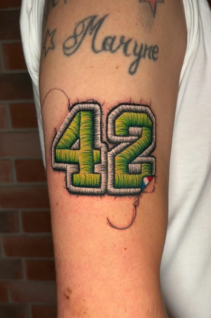 Embroidery tattoo of the number 42 on an arm, showcasing realistic stitching detail.