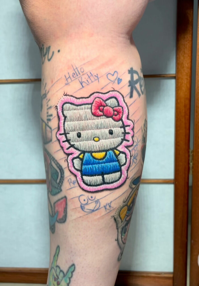 Embroidery tattoo of Hello Kitty on an arm, featuring realistic stitching details and vibrant colors.