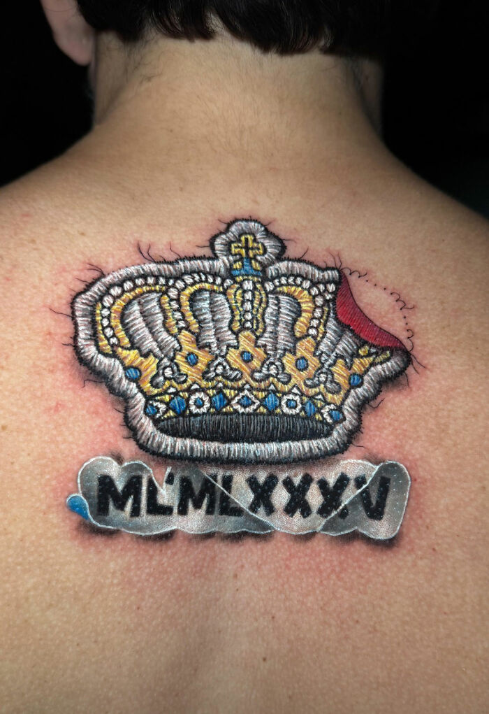 Embroidery tattoo of a crown with intricate details on a person's back, showcasing realistic artistry.