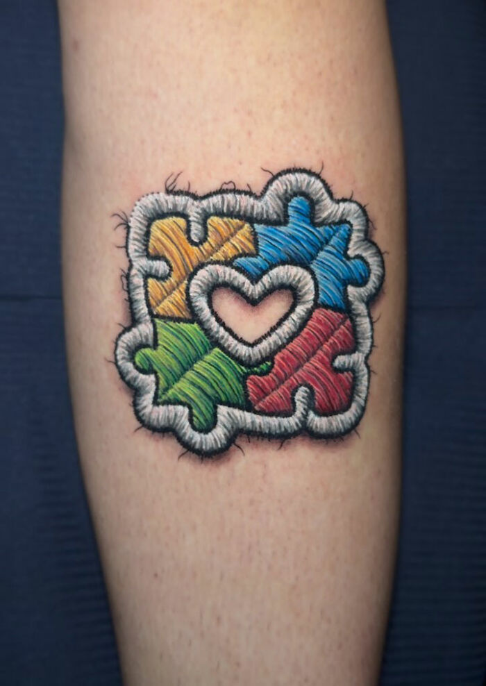Embroidery tattoo of colorful puzzle pieces with a heart shape, showcasing realistic embroidery art.