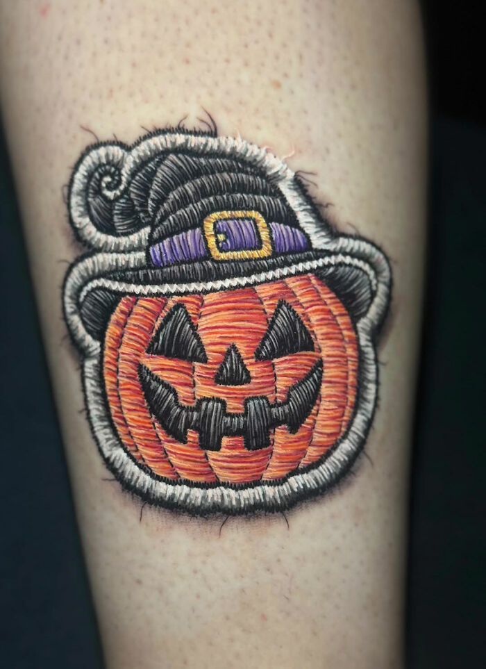 Realistic embroidery tattoo of a pumpkin wearing a witch hat, showcasing intricate stitching details.