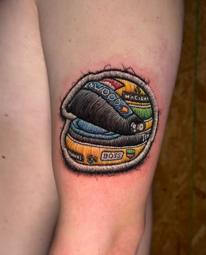 Realistic-looking embroidery tattoo of a colorful spool on a person's arm.