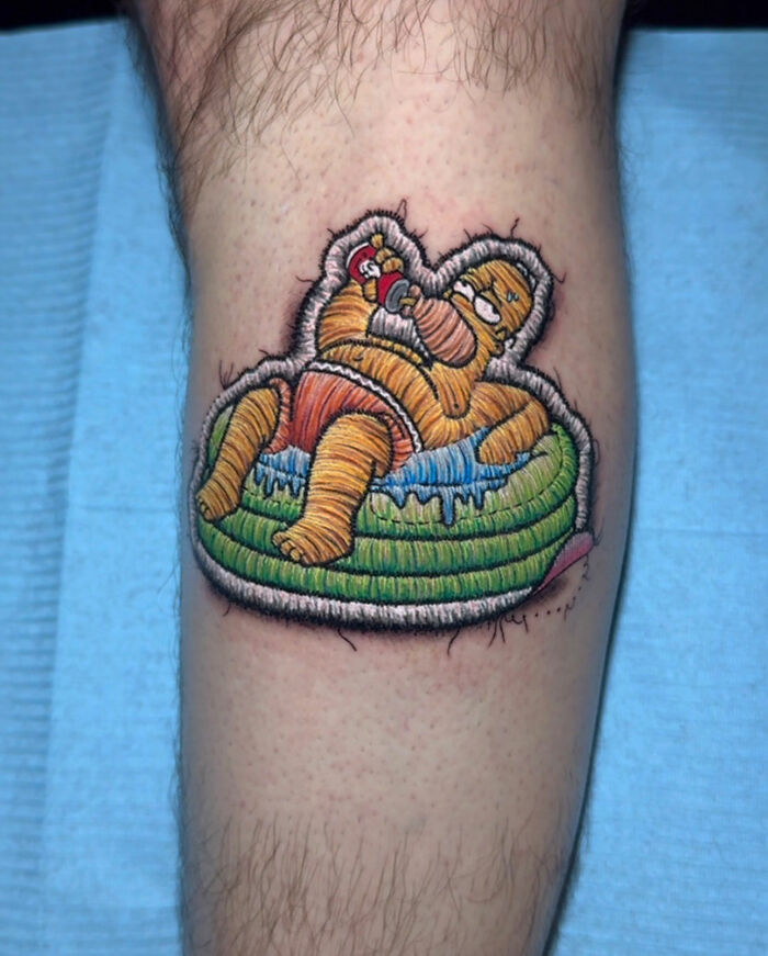 Realistic-looking embroidery tattoo of a cartoon character lounging on a pool float.