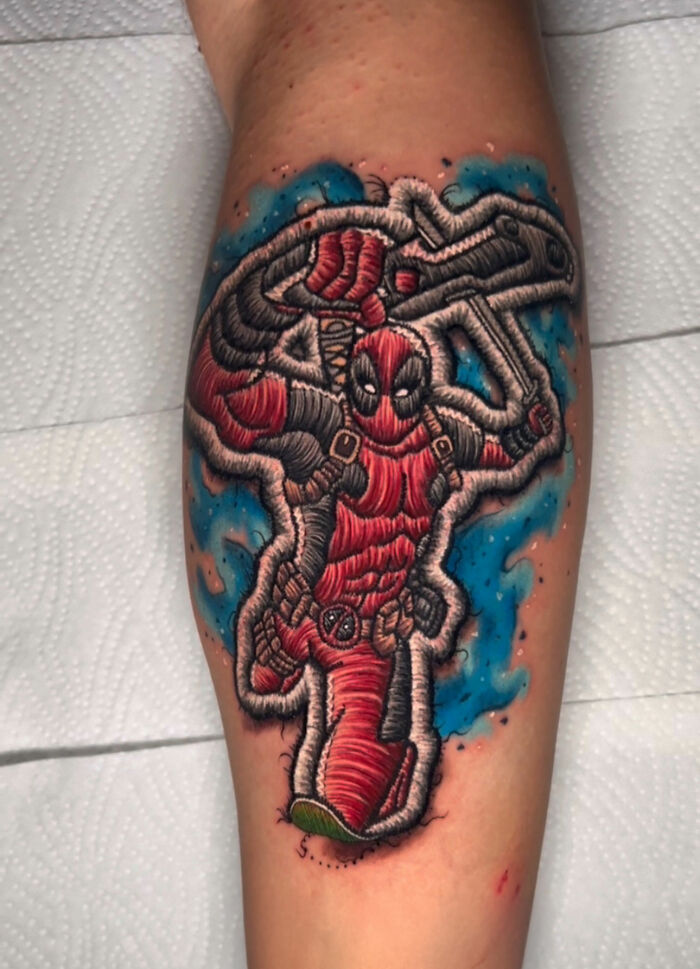 Realistic embroidery tattoo of a character with swords and red suit on forearm.