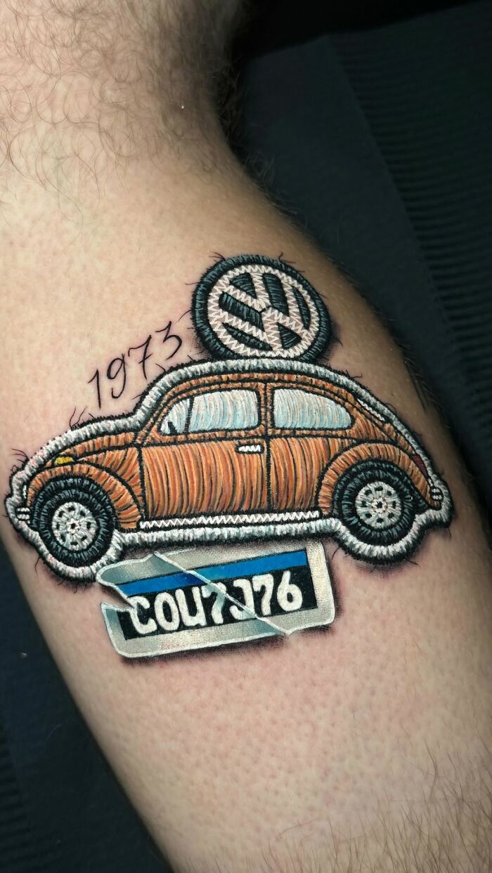 Realistic embroidery tattoo of a vintage car with the year 1973, showcasing intricate details on a person's arm.