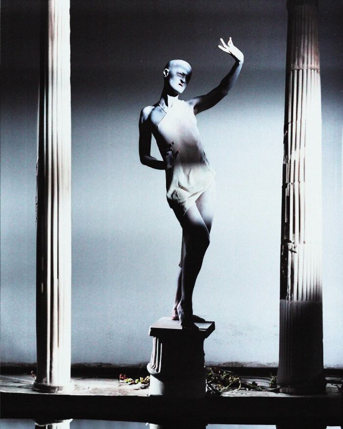 Unique model posing between columns, exuding an artistic and ethereal vibe.