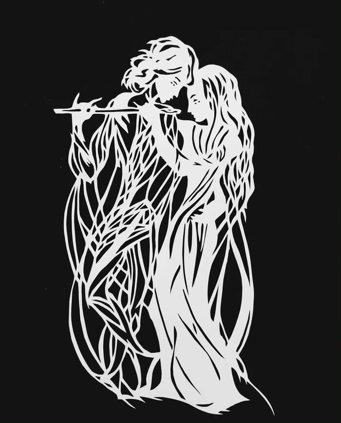 Intricate paper-cutting art depicting two figures embracing, showcasing delicate craftsmanship and creativity.