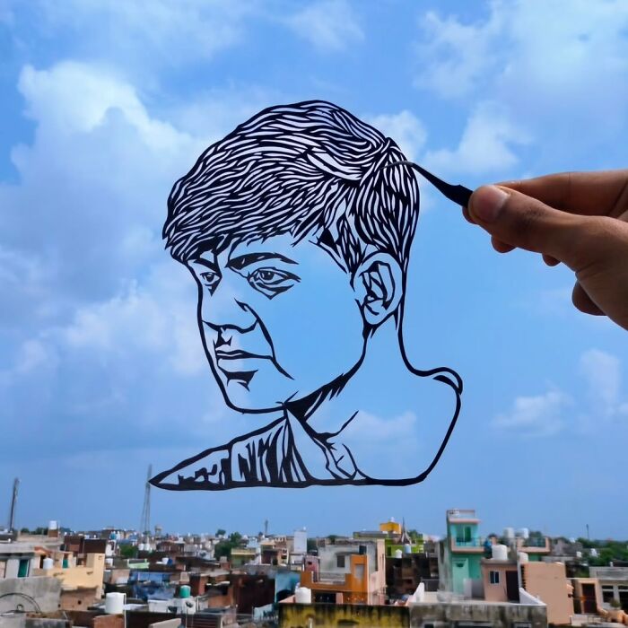Hand holding a paper-cut portrait against a city skyline; intricate paper-cutting art displayed.