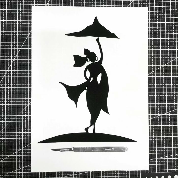 Paper-cutting art of a silhouetted dancer on white paper with a scalpel below.