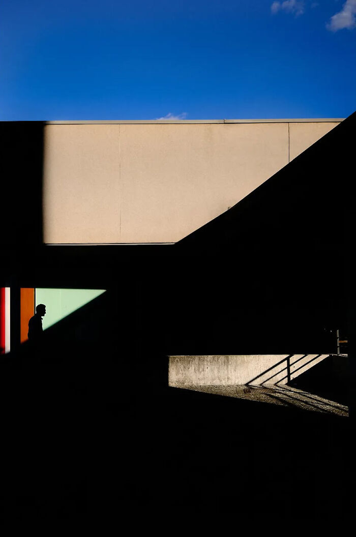 Abstract street photograph by Andrea Pozzoni capturing shadows and geometric shapes against a vibrant blue sky.