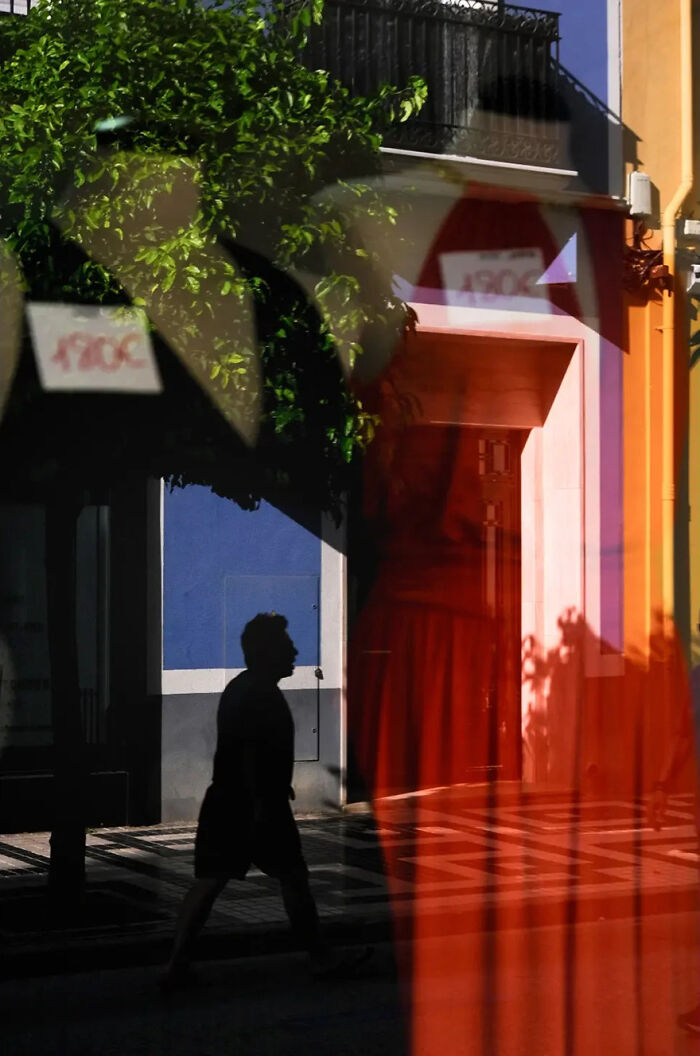 Abstract street photograph by Andrea Pozzoni featuring silhouettes and reflections in vibrant urban colors.