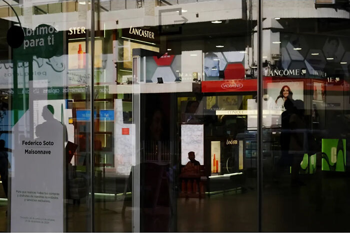 Abstract street photograph by Andrea Pozzoni featuring reflections and storefronts in an urban setting.