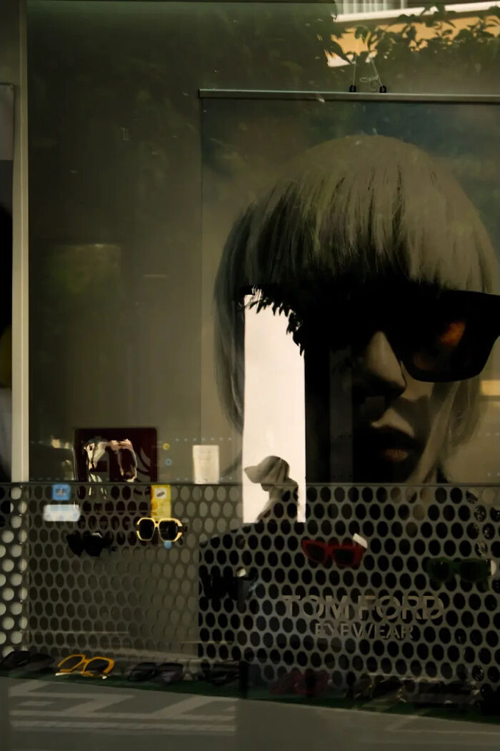 Abstract street photograph by Andrea Pozzoni featuring a window reflection with sunglasses display.